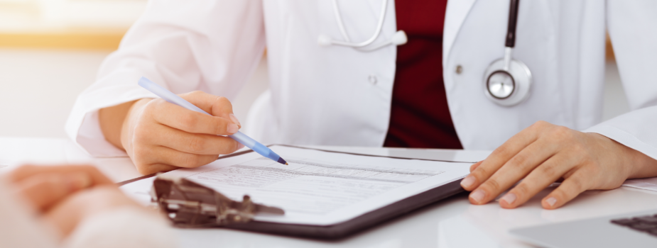 médecin en blouse blanche écrivant sur une feuille de soins à la fin d'une consultation