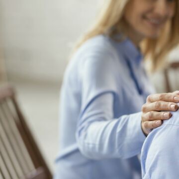 Consultation chez un psychologue qui pose la main sur l'épaule de sa patiente pour la soutenir pendant son burn out. Freepik.