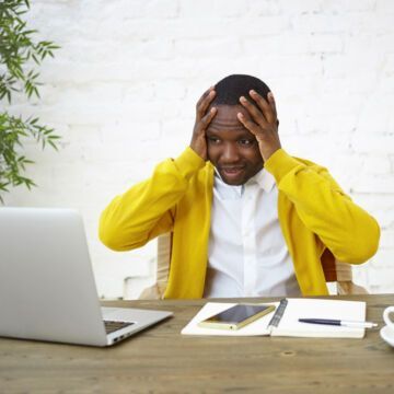 Jeune homme avec une surcharge de travail, proche du burn out, devant son ordinateur. Freepik