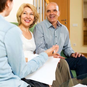 Couple de quinquagénaires avec leur conseiller mutualiste. Souriant car leur conseiller est à l'écoute. Freepik.