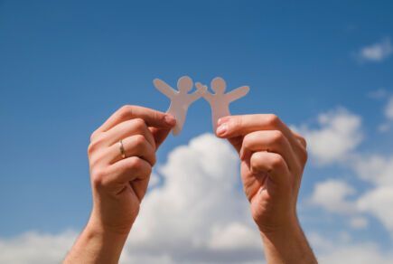 Mains qui tiennent des petits bonhommes de papier pour symboliser la solidarité à la base de la protection universelle maladie. Freepik.