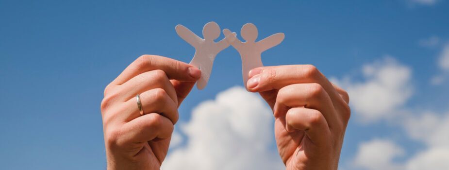 Mains qui tiennent des petits bonhommes de papier pour symboliser la solidarité à la base de la protection universelle maladie. Freepik.