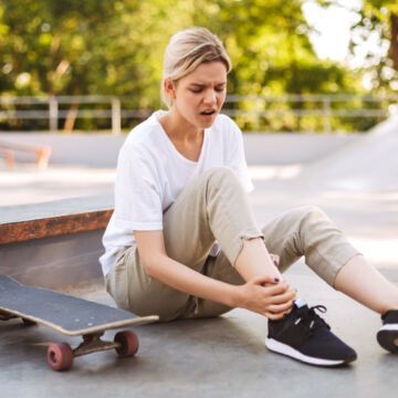 Jeune femme qui fait du skateboard et a mal à la jambe. Freepik