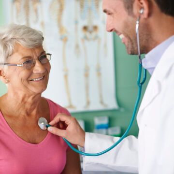 Dame qui sourit pendant que le médecin lui passe un stéthoscope sur le coeur. Freepik