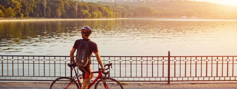 Personne qui fait du vélo pour rester en bonne santé, au bord d'un lac avec du soleil.